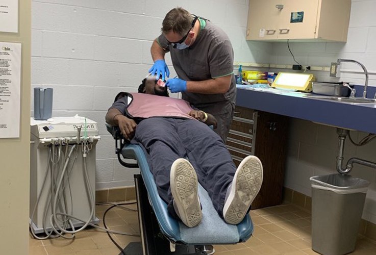 Dentist examining patient in dental exam chair