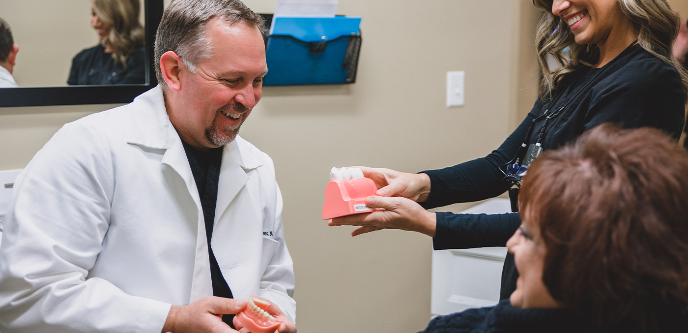 Dentist and dental team member showing patient model smile after cosmetic dentistry