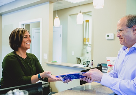 Dental team member handing patient payment information package