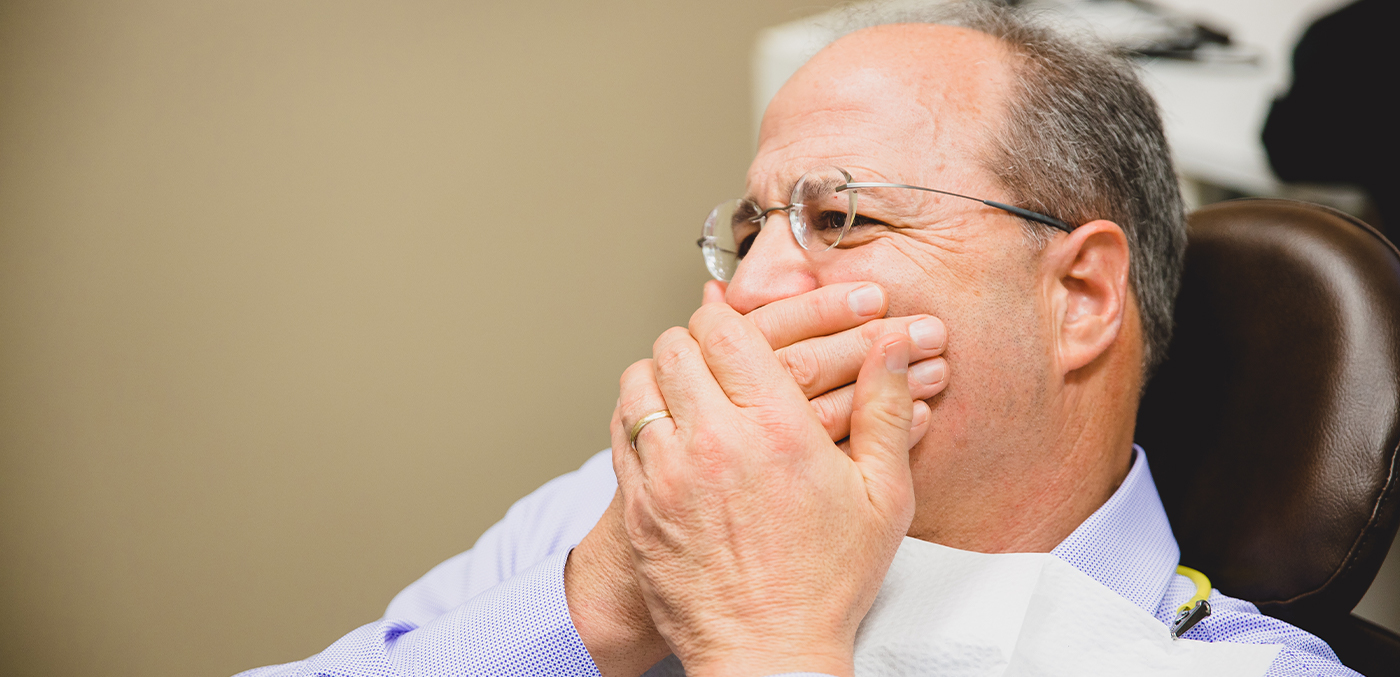 Man in need of emergency dentistry covering his mouth