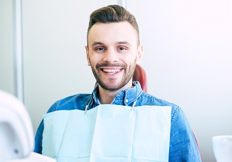 A young male with a beard sitting in the dentist’s chair waiting to see the dentist for a checkup and cleaning