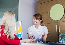 Employee explaining cost of dental implants in Geneva to patient