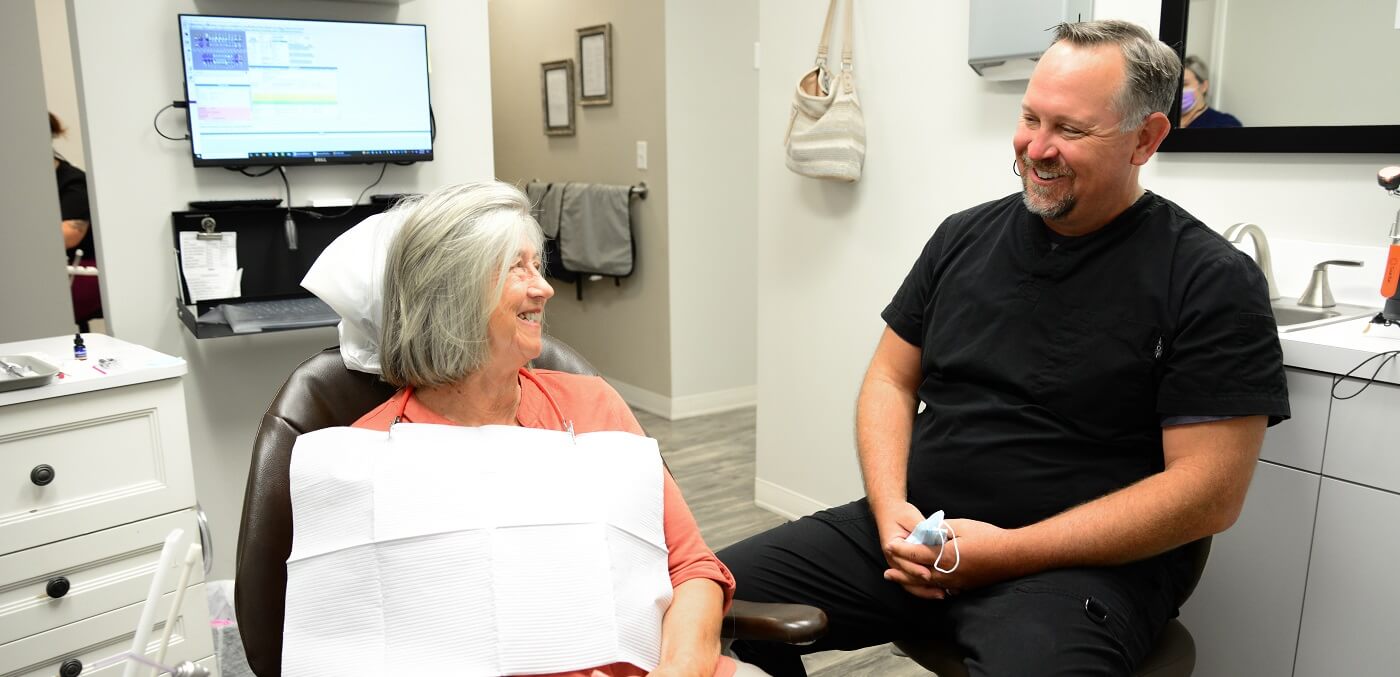 Senior woman in dental chair talking to her dentist in Geneva