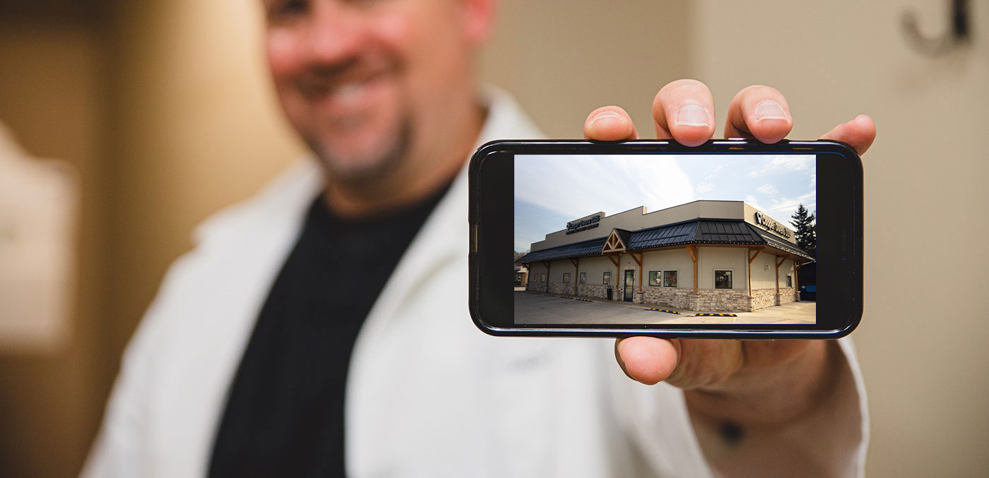 Dentist holding up phone with design image of new Geneva Dental Office