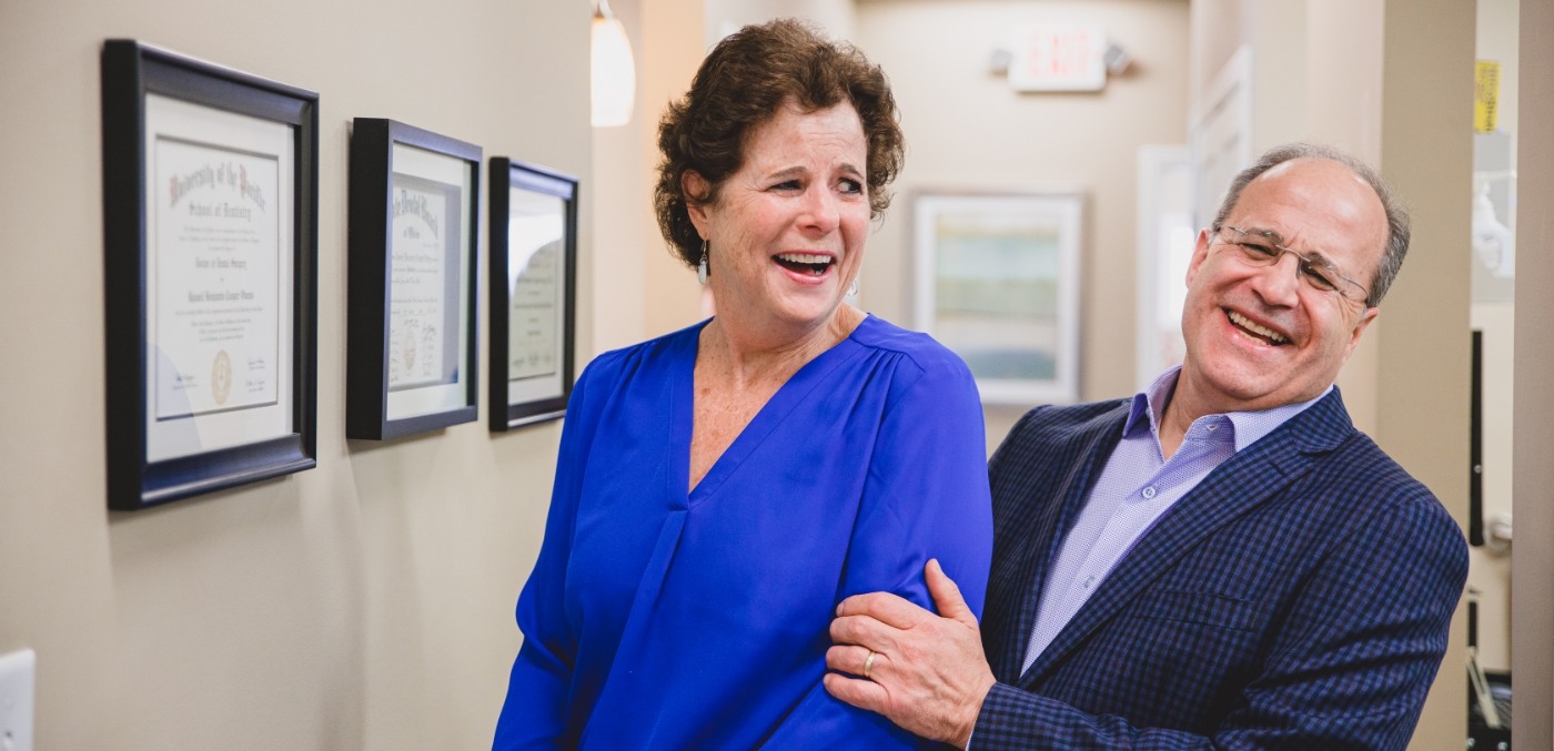 Laughing man and woman in dental office for periodontal therapy