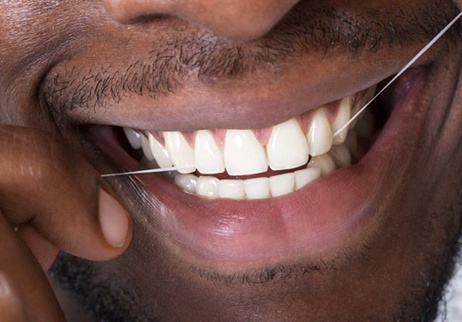Closeup of man flossing after at-home teeth whitening in Geneva